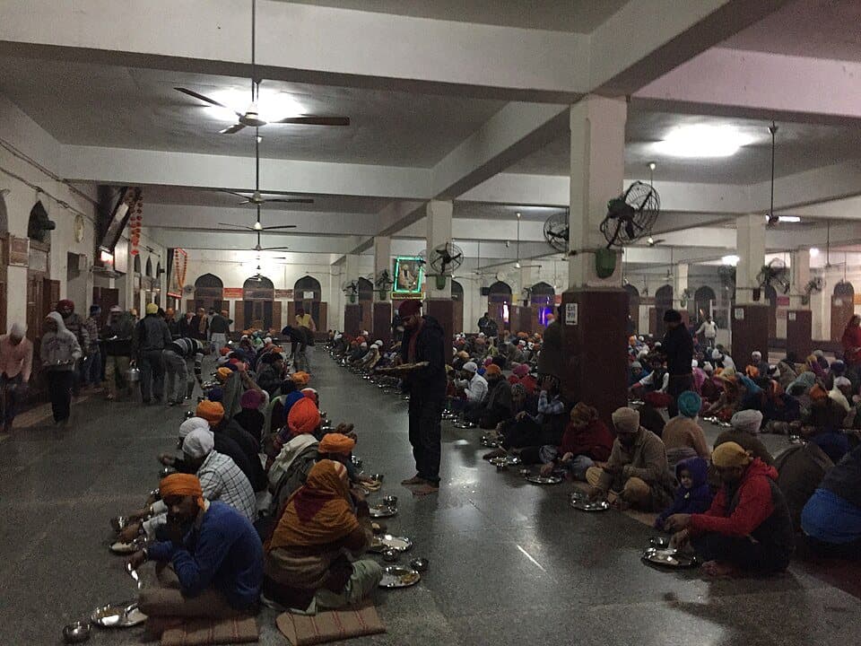 Sangat sitting together in rows on the floor of a langar hall